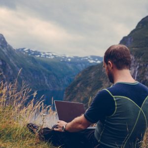Mann mit Notebook in den Bergen